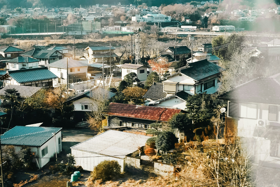 An aerial view of a Japanese town with traditional homes and surrounding greenery.