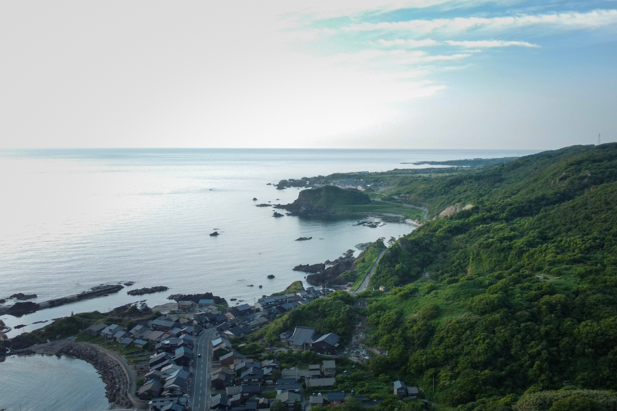 Aerial view of Sado Island’s rugged coastline and villages along the Sea of Japan, symbolizing its history of exile and renewal.